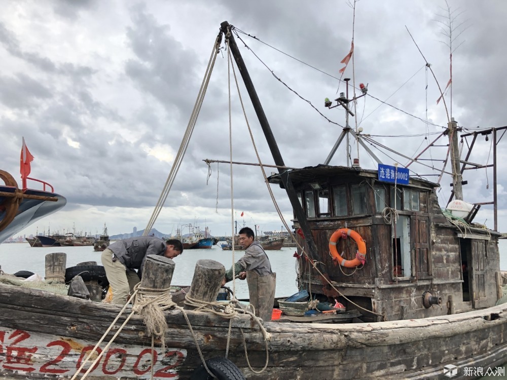 用铁锹奋力往渔船外铲鱼的渔民